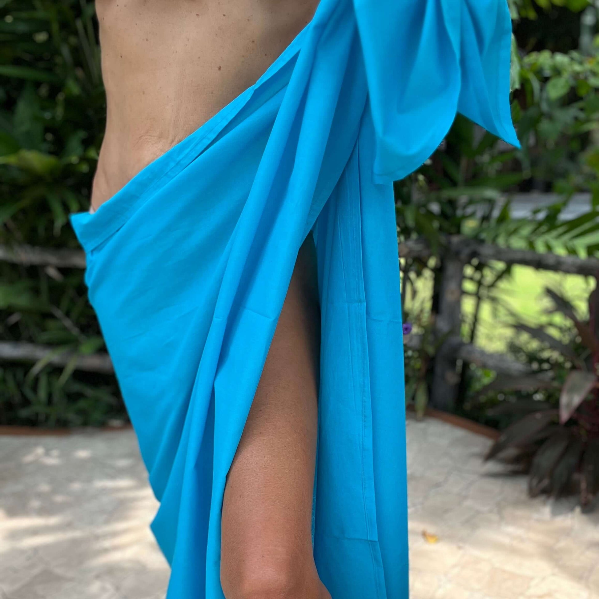 Island blue cotton sarong styled on beach model wearing sarong hut design
