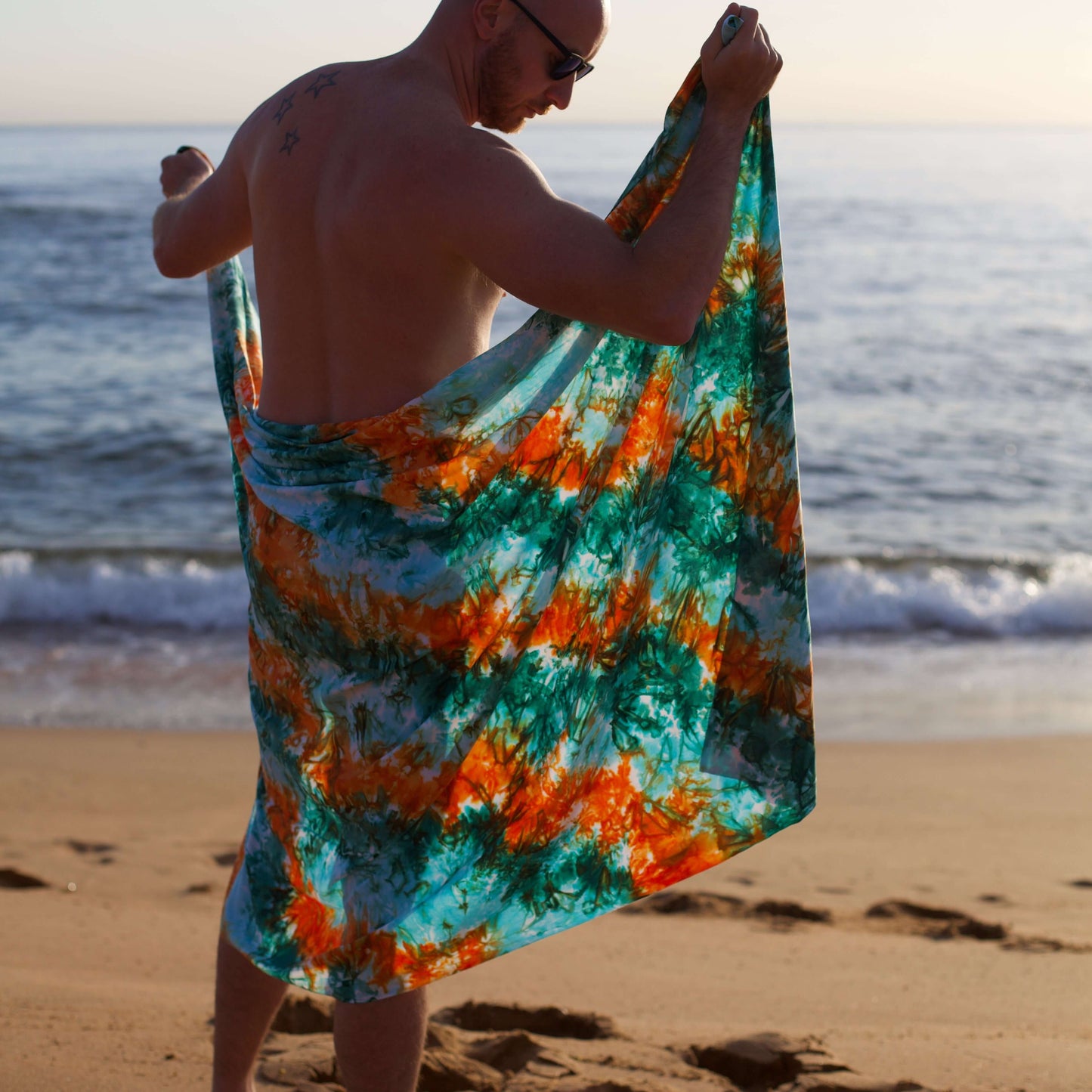Oasis luxe mens sarong in orange and green broad view on beach