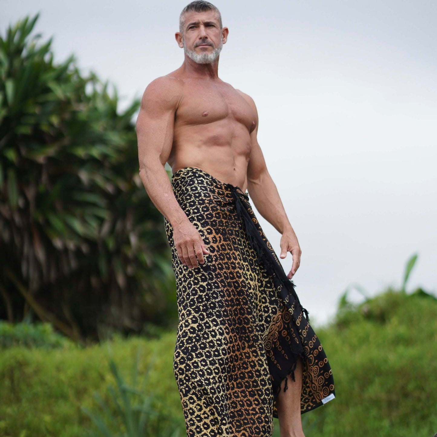 Suva mens beach sarong styled on beach model wearing sarong hut design