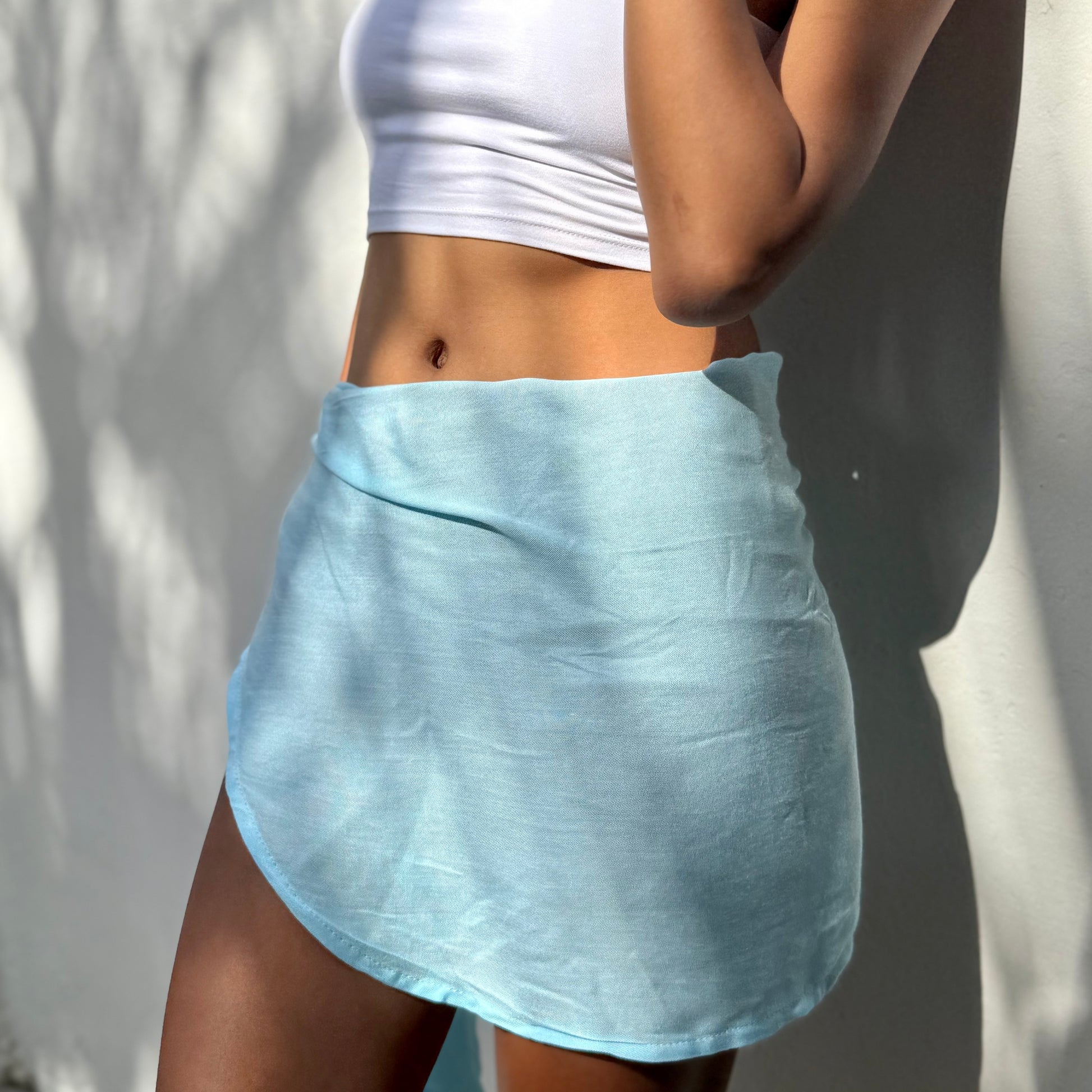 Mini sarong aqua beachwear look, photographed outdoors in natural light