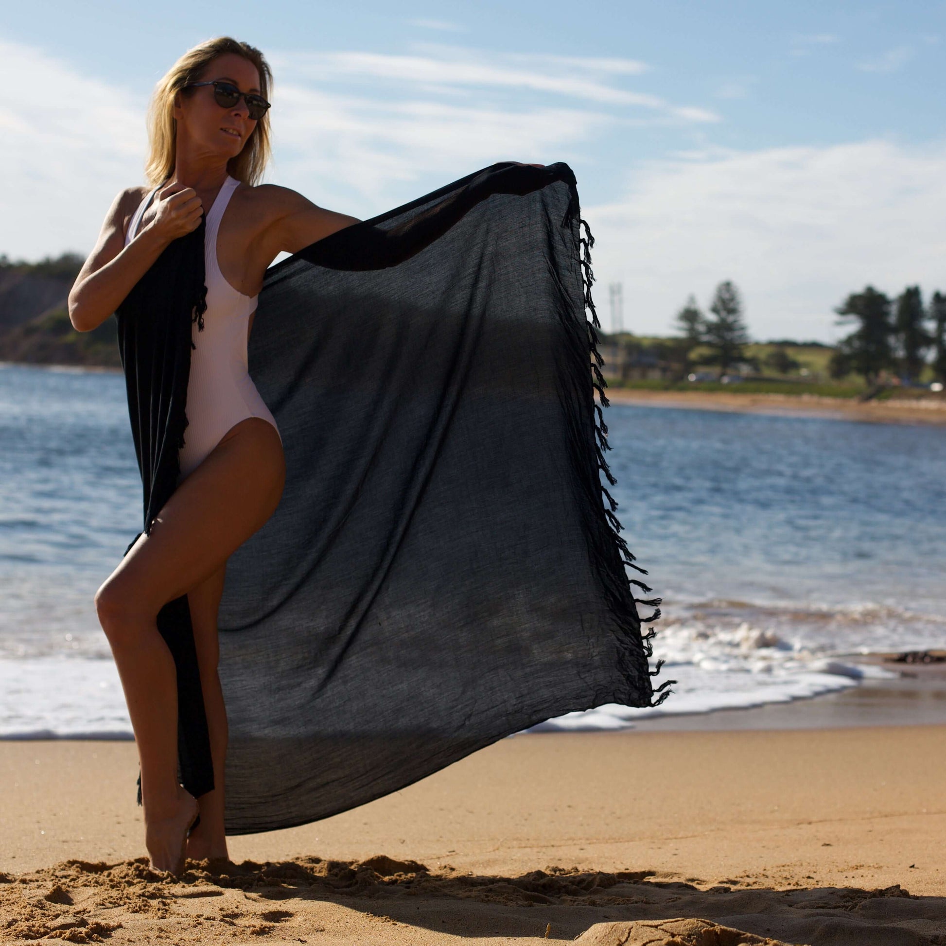 Woman on a sydney beach showcasing a classic black beach swimsuit cover-up