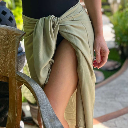 Olive beach sarong styled on beach model wearing sarong hut design